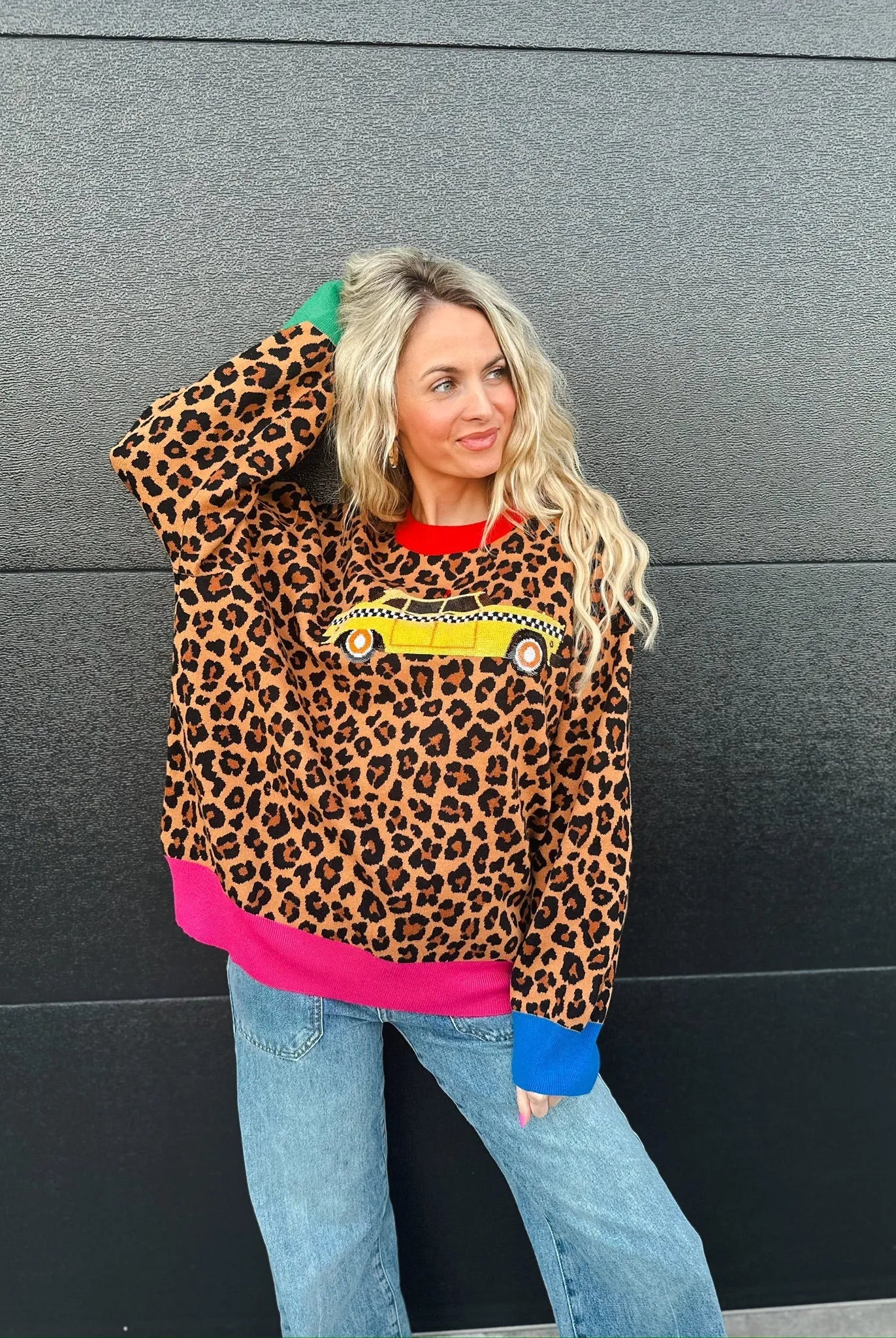 Queen of Sparkles leopard print sweater with yellow taxi cab graphic, red collar, pink hem, and blue cuffs.