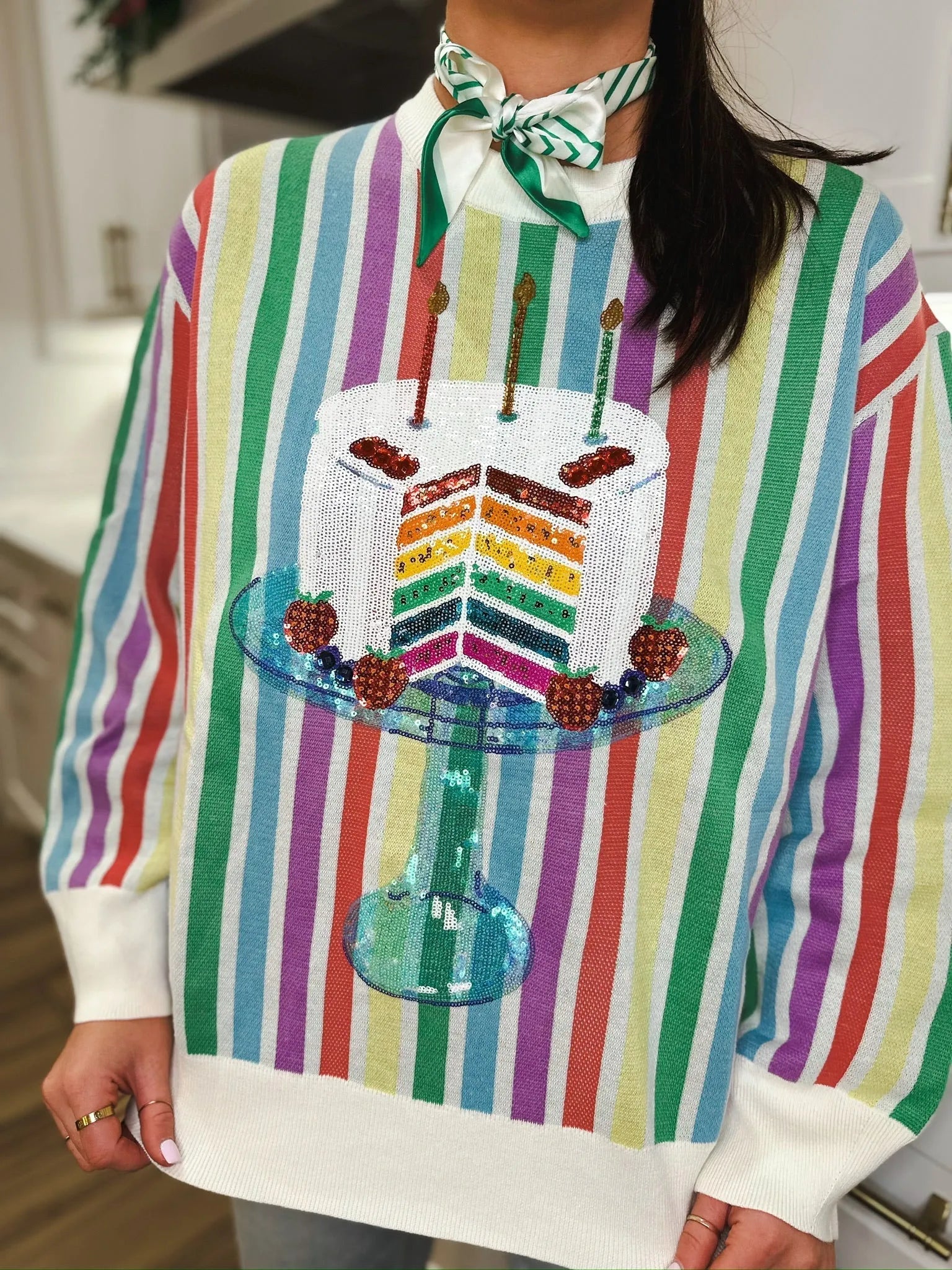 Rainbow Stripe Birthday Cake Sweater with sequin cake graphic. Cake has rainbow layers, candles, and fruit decorations.