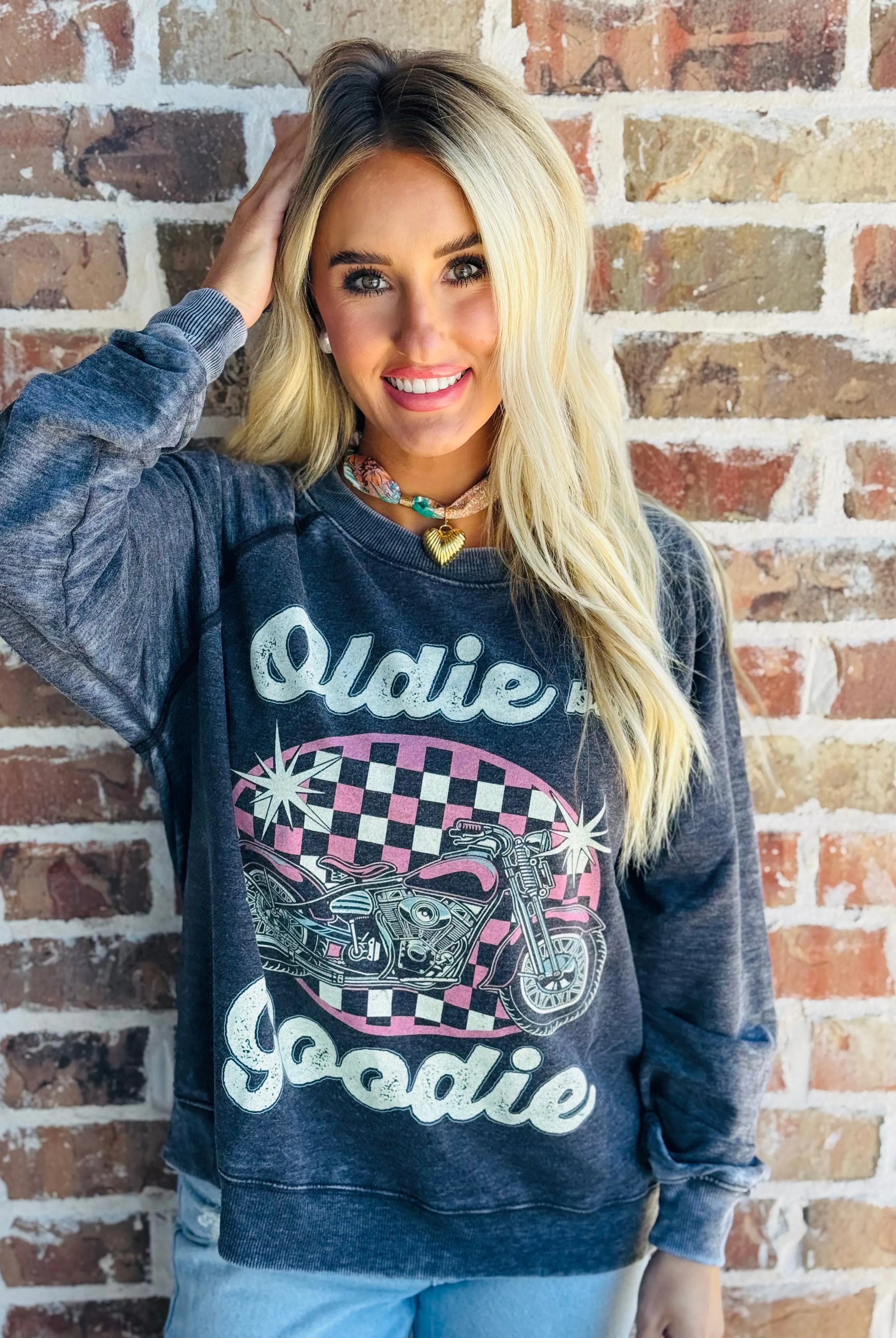 Recycled Karma "Oldie But Goodie" graphic sweatshirt with a pink motorcycle and checkered oval on a charcoal gray background.