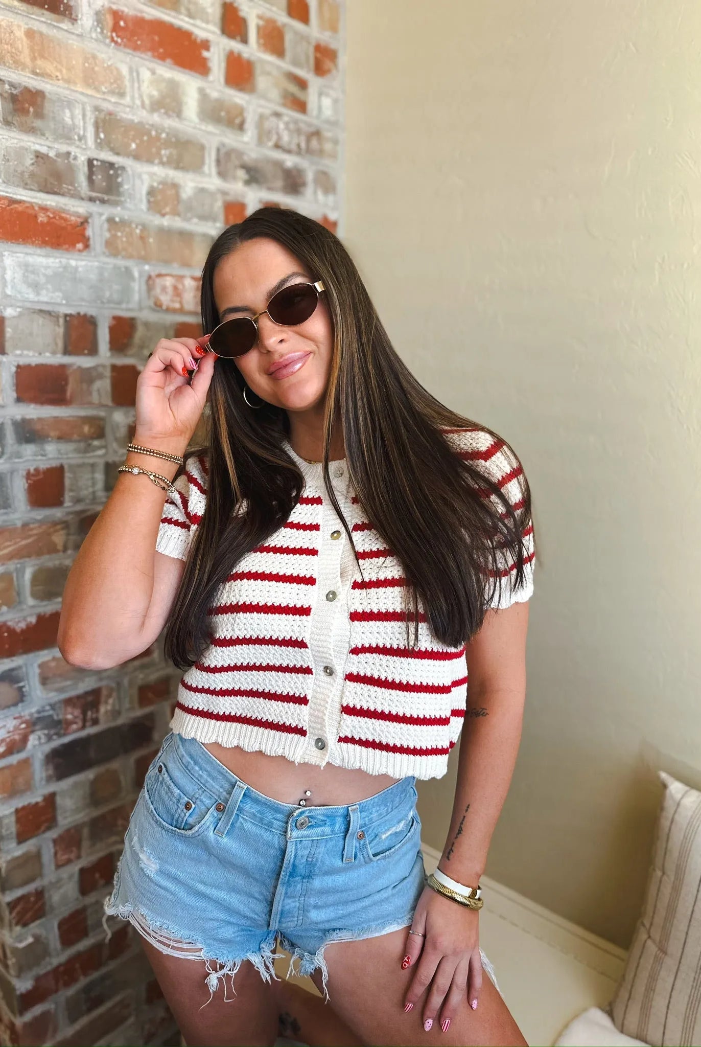 Cropped red and cream horizontal striped short sleeve button down cardigan sweater with white buttons.