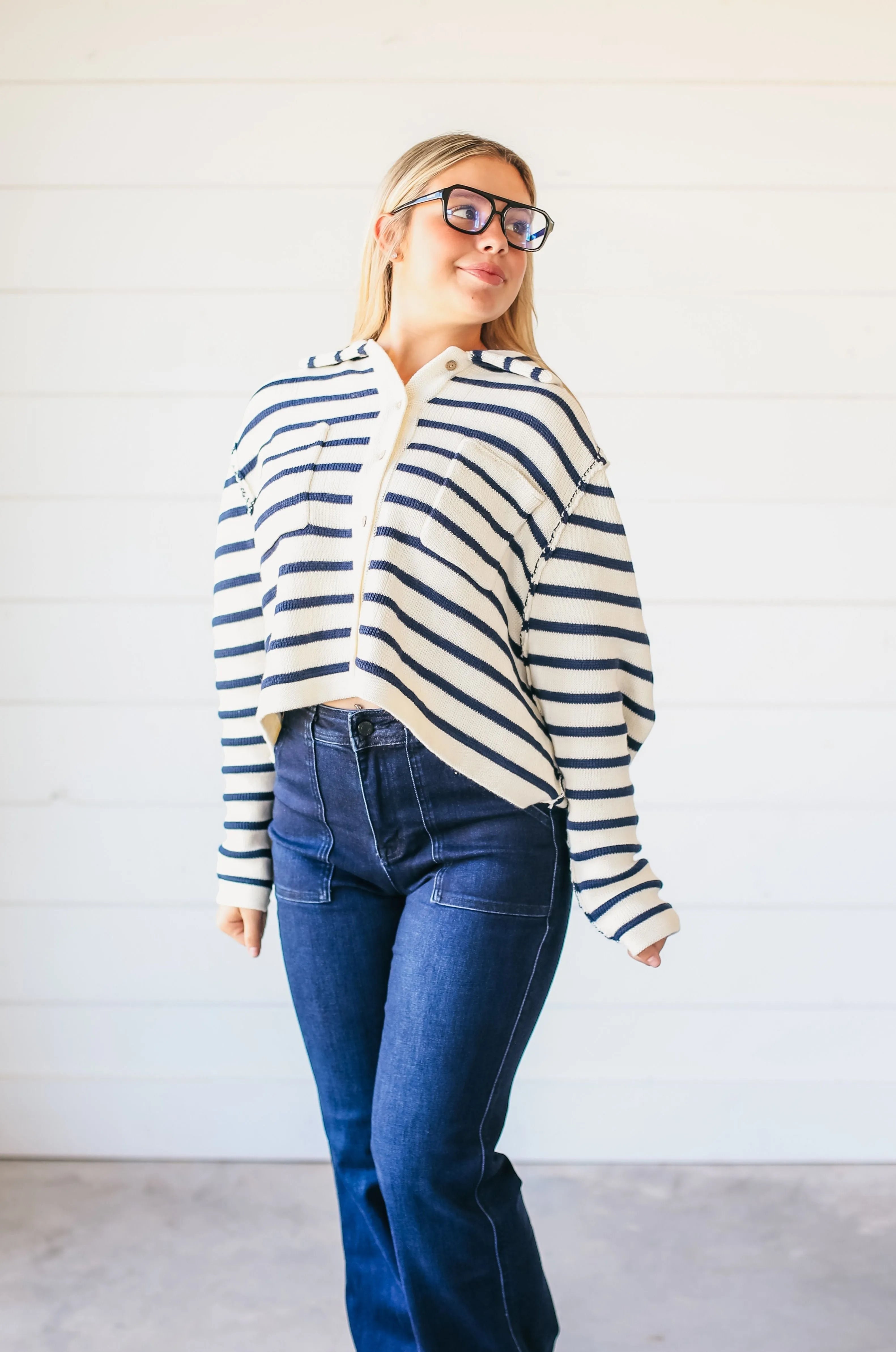 Relaxed fit cream and navy striped button-down sweater with collar and front pockets, worn by a woman with glasses.