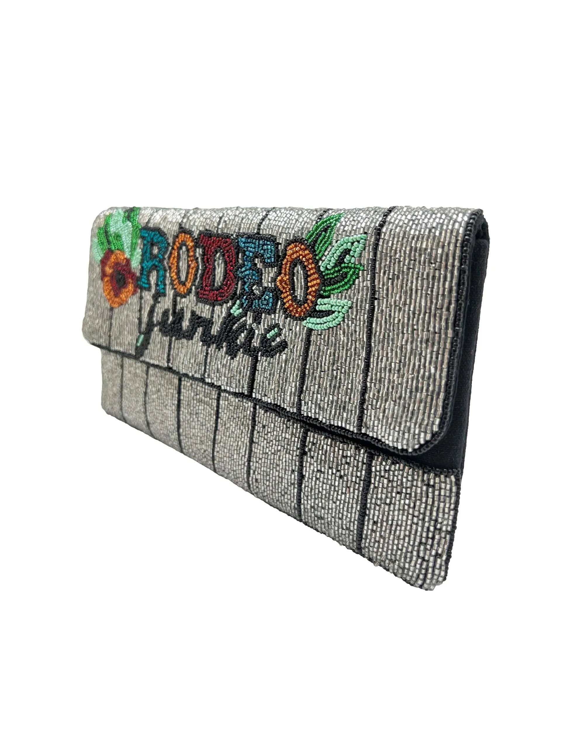 Silver beaded clutch with vertical stripes and colorful embroidered text "RODEO JUNKIE" and floral accents.