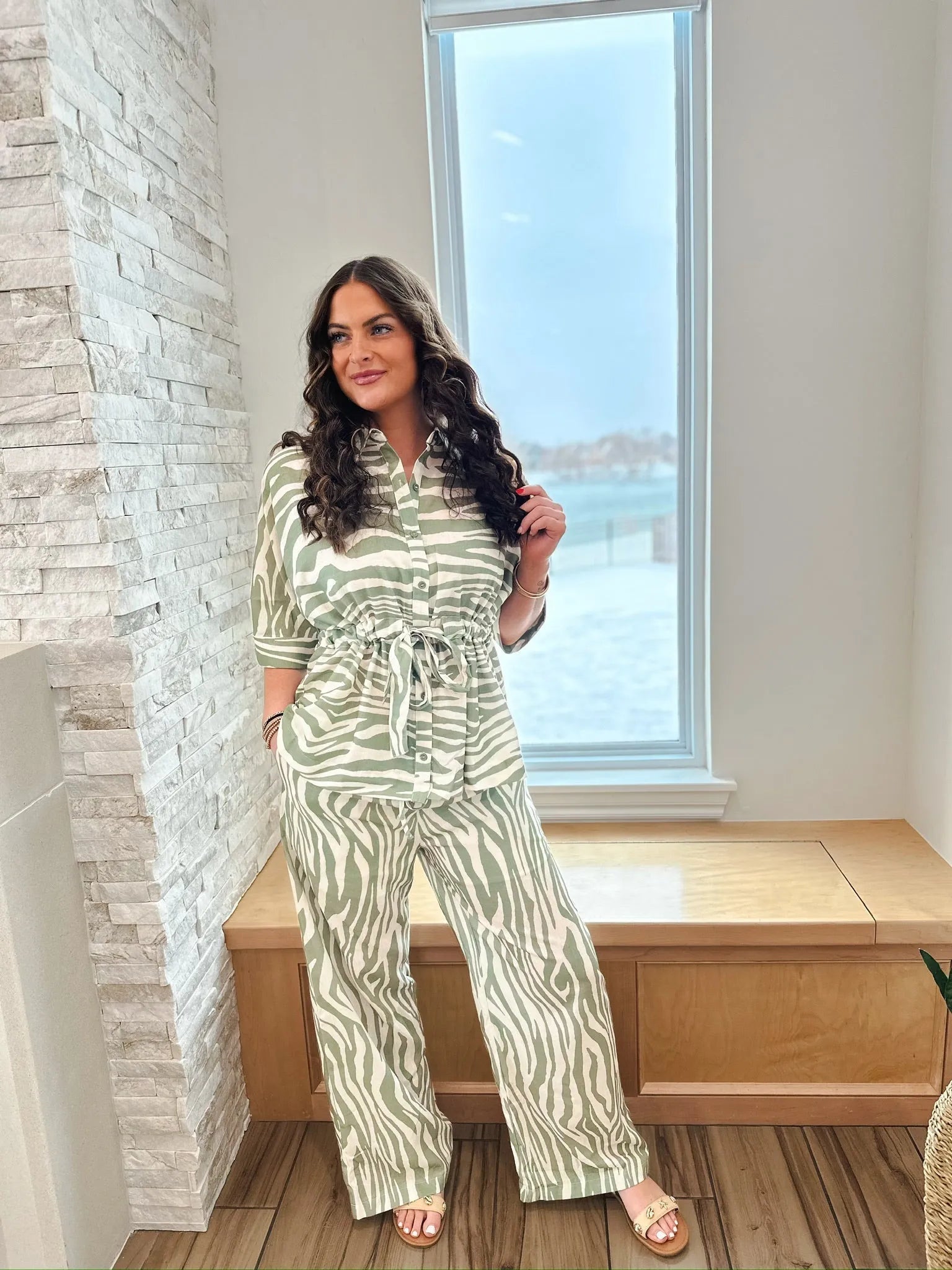Sage and cream zebra print matching set by ENTRO: A woman wears a belted button-down shirt and wide-leg pants with a zebra