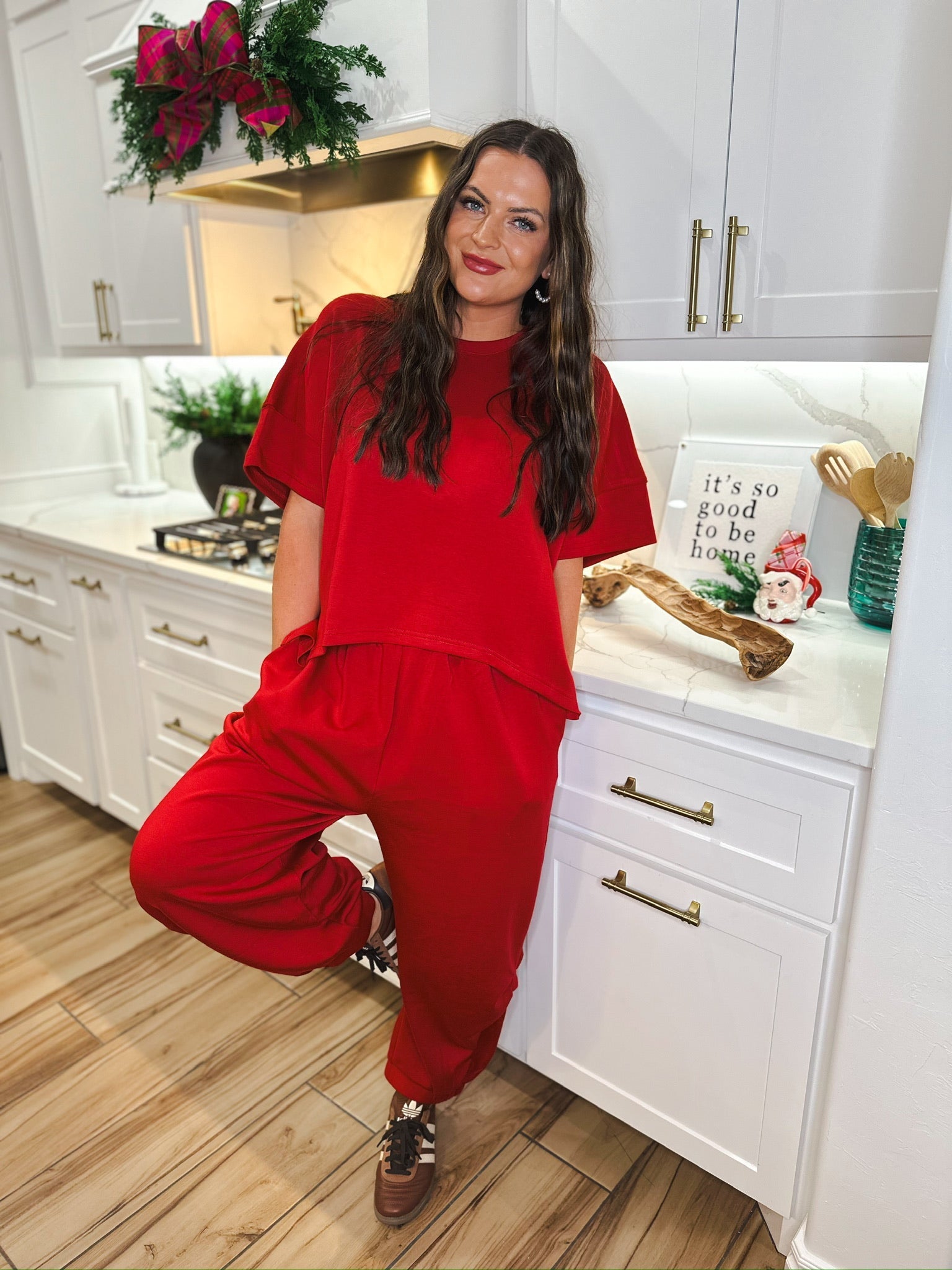 Woman wearing a solid red round neck top and semi harem pants. The outfit has a relaxed fit and is paired with brown