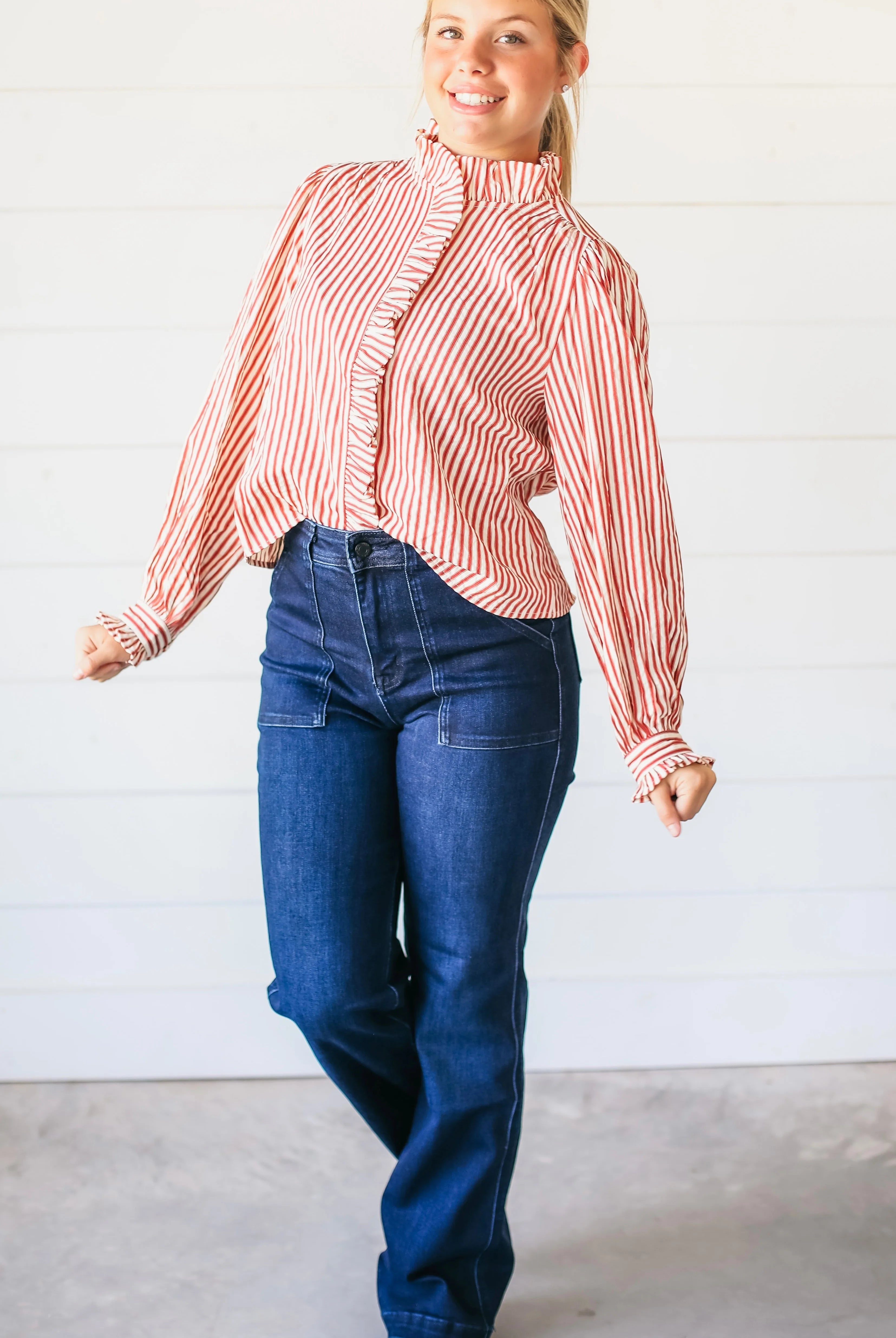 Woman wearing dark wash super high rise vintage flare jeans with prominent front pocket detail and a red and white striped