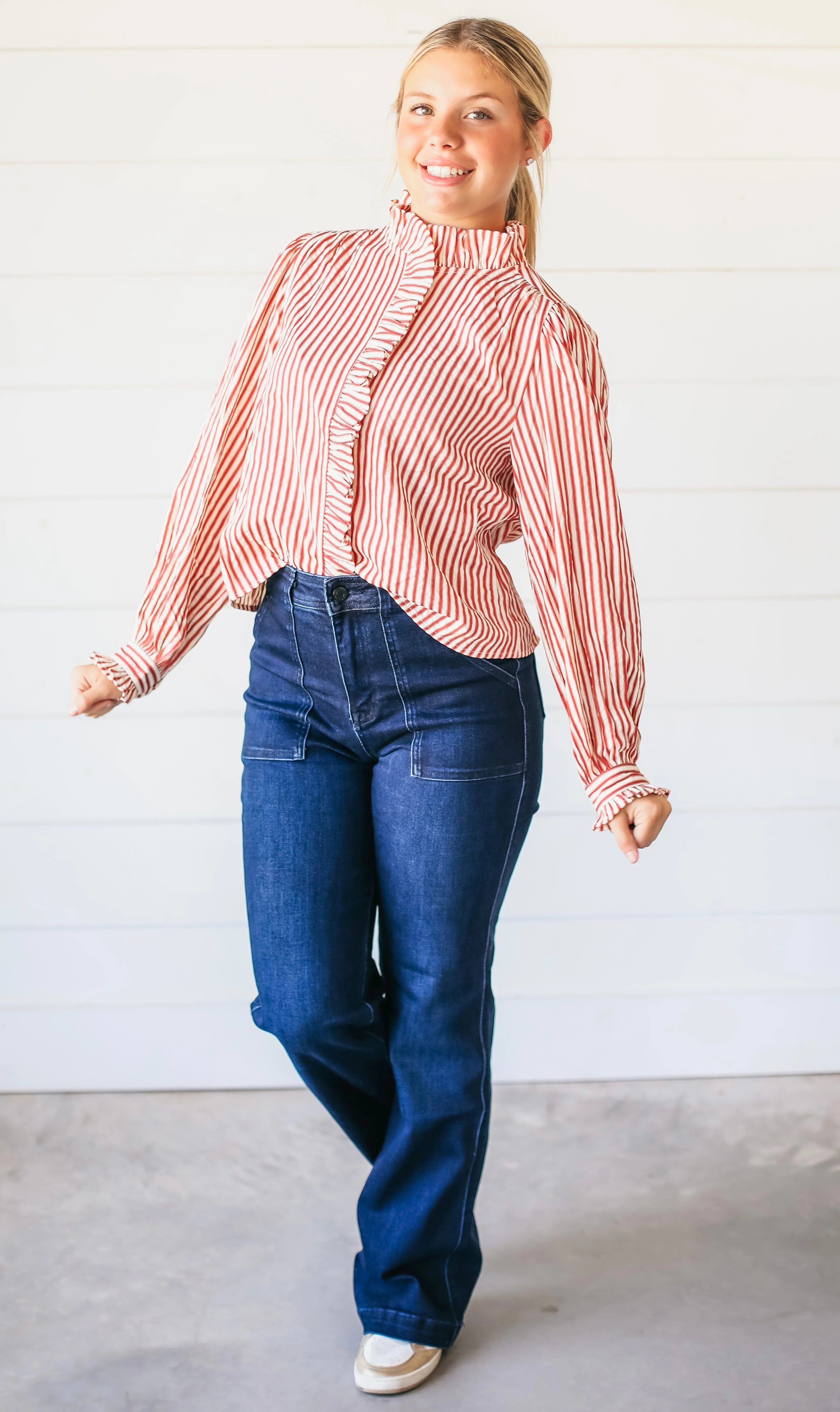 Woman wearing dark wash super high rise vintage flare jeans with prominent front pocket detail and a red and white striped