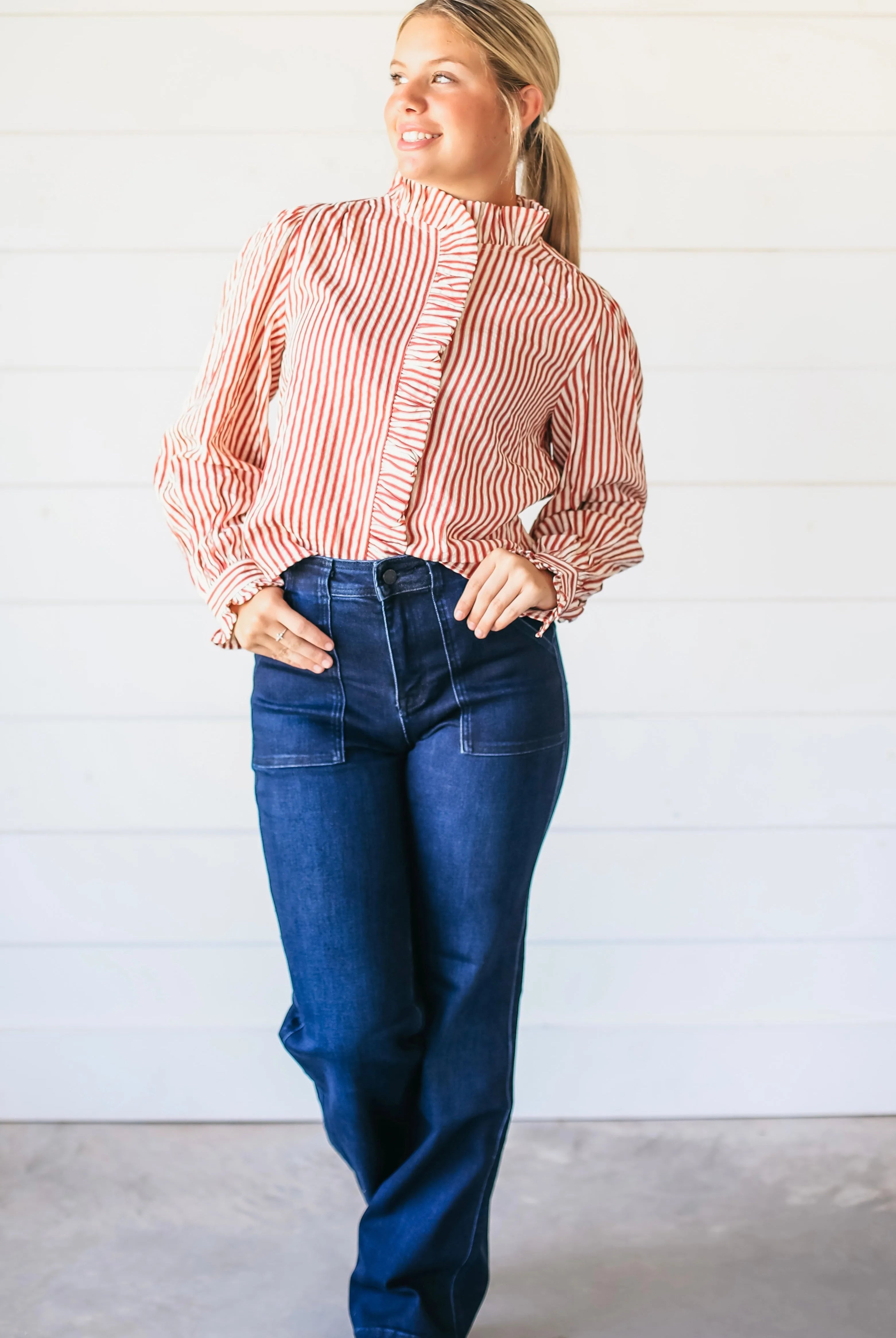 Woman wearing dark wash super high rise vintage flare jeans with two front patch pockets and a red and white striped