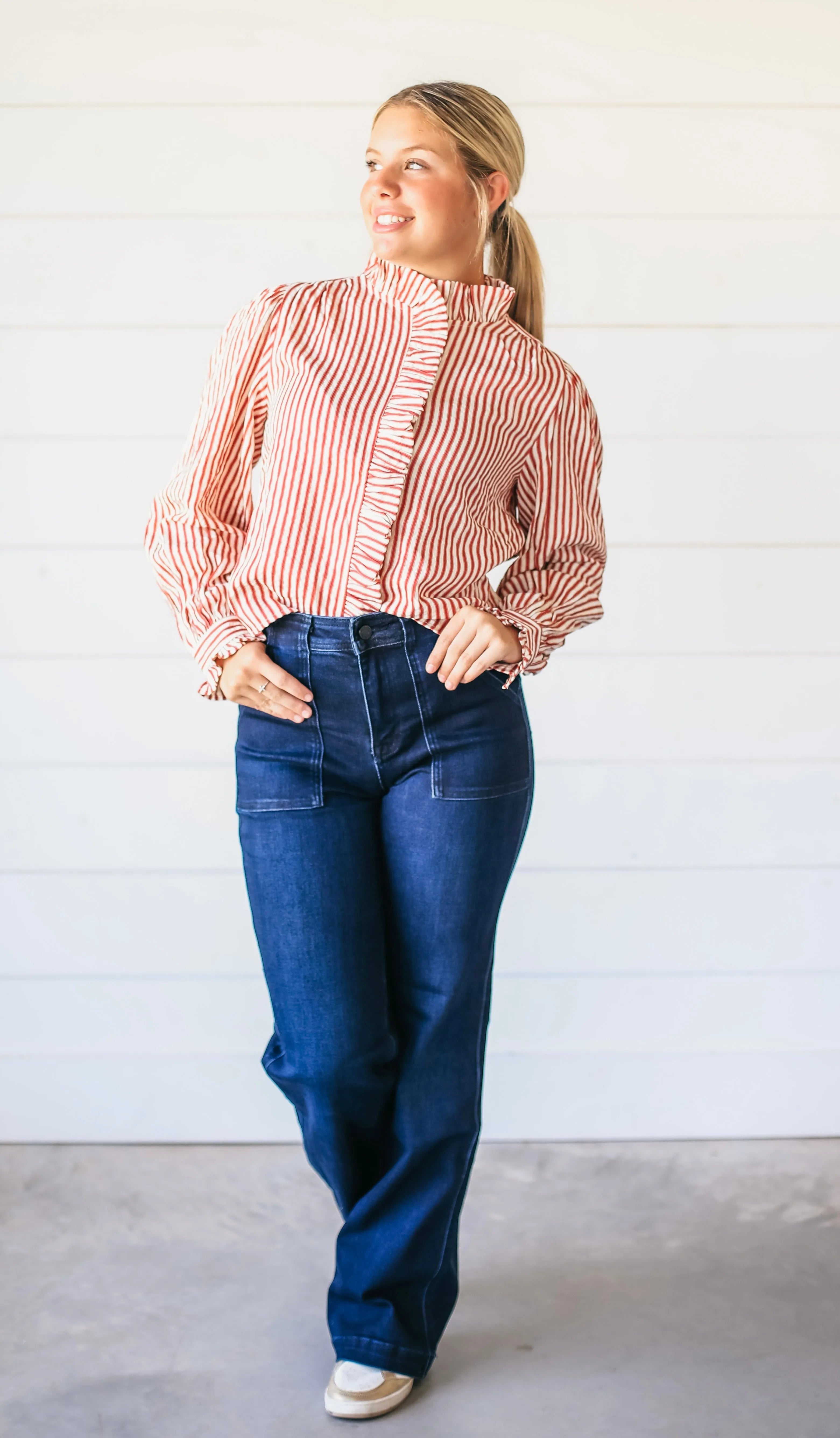 Woman wearing dark wash super high rise vintage flare jeans with two front patch pockets and a red and white striped
