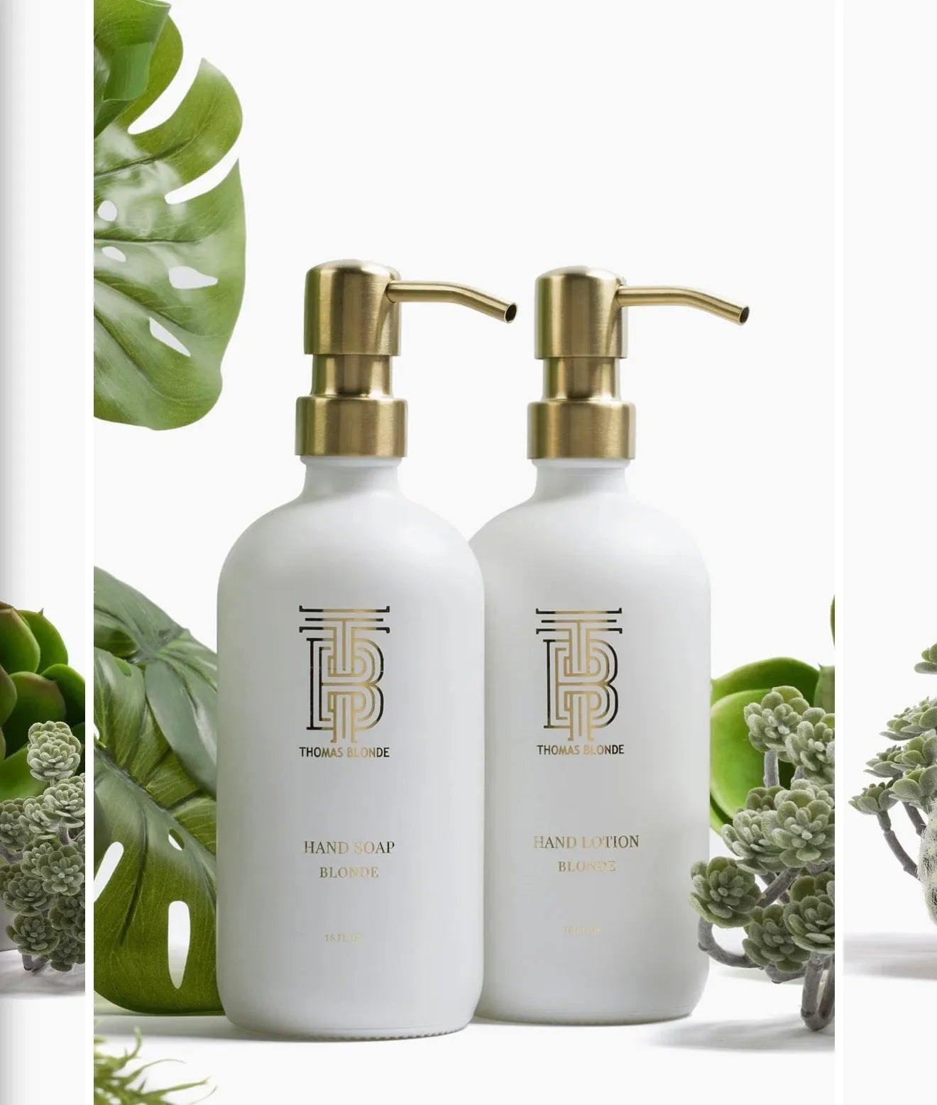 Two white Thomas Blonde dispenser bottles with gold pumps, one for hand soap, one for hand lotion, surrounded by greenery.