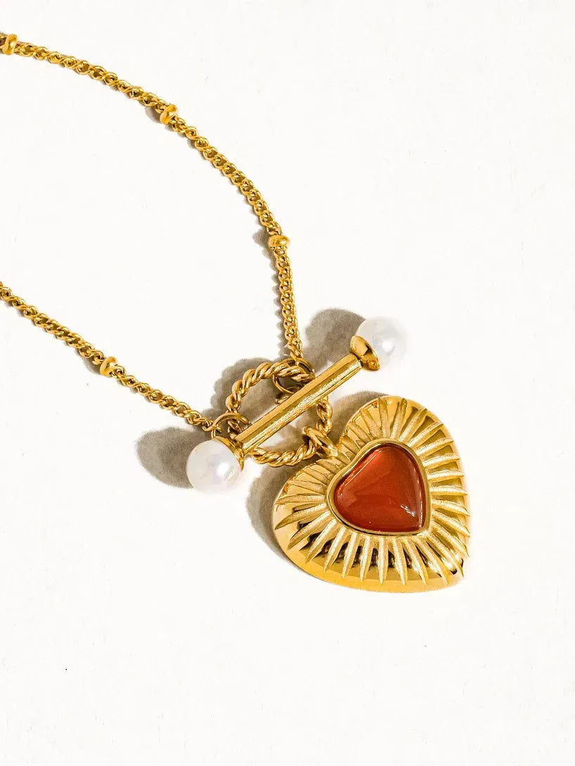 Gold heart necklace with carved agate center and pearl accents, featuring a toggle clasp.
