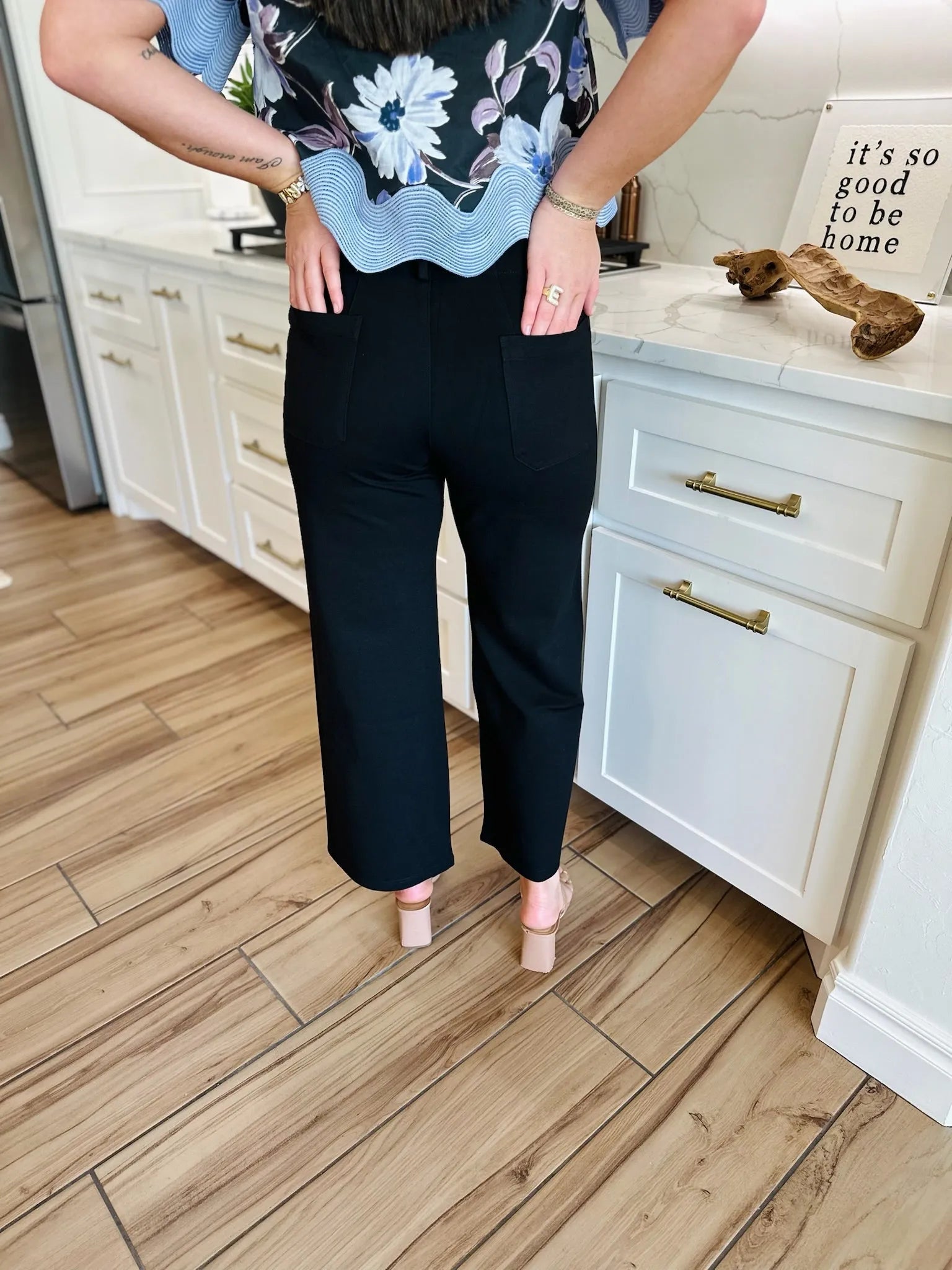 Back view of Womens black ponte wide leg pants with two back pockets and a cropped hem, worn with nude block heels.