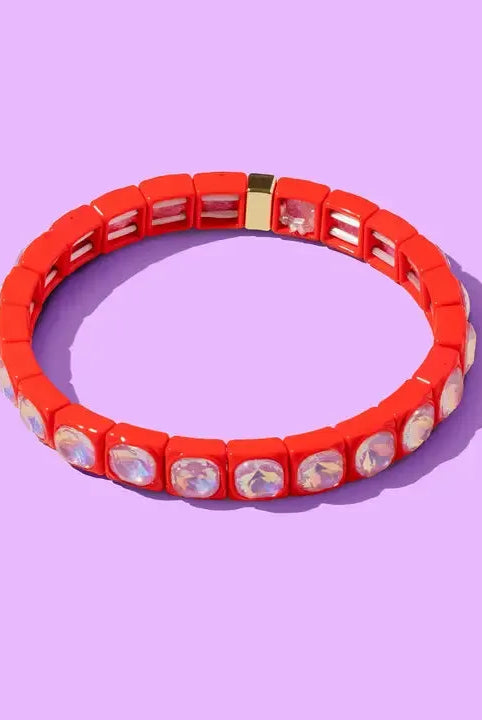 Red enamel stacking bracelet with clear square rhinestones and a gold clasp on a purple background.