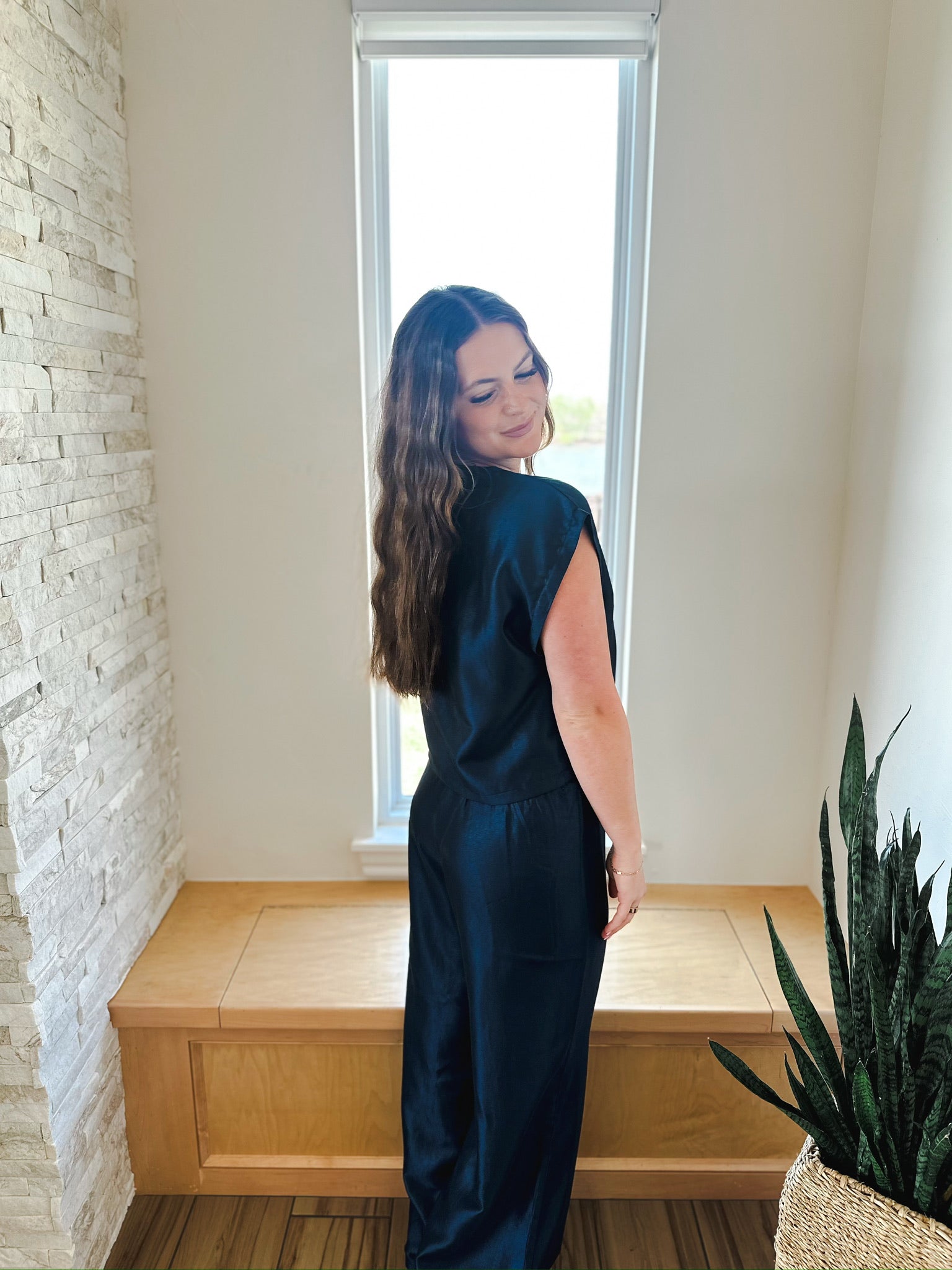 Woman wearing a navy blue shimmer short sleeve top and matching wide-leg pants. Back view.