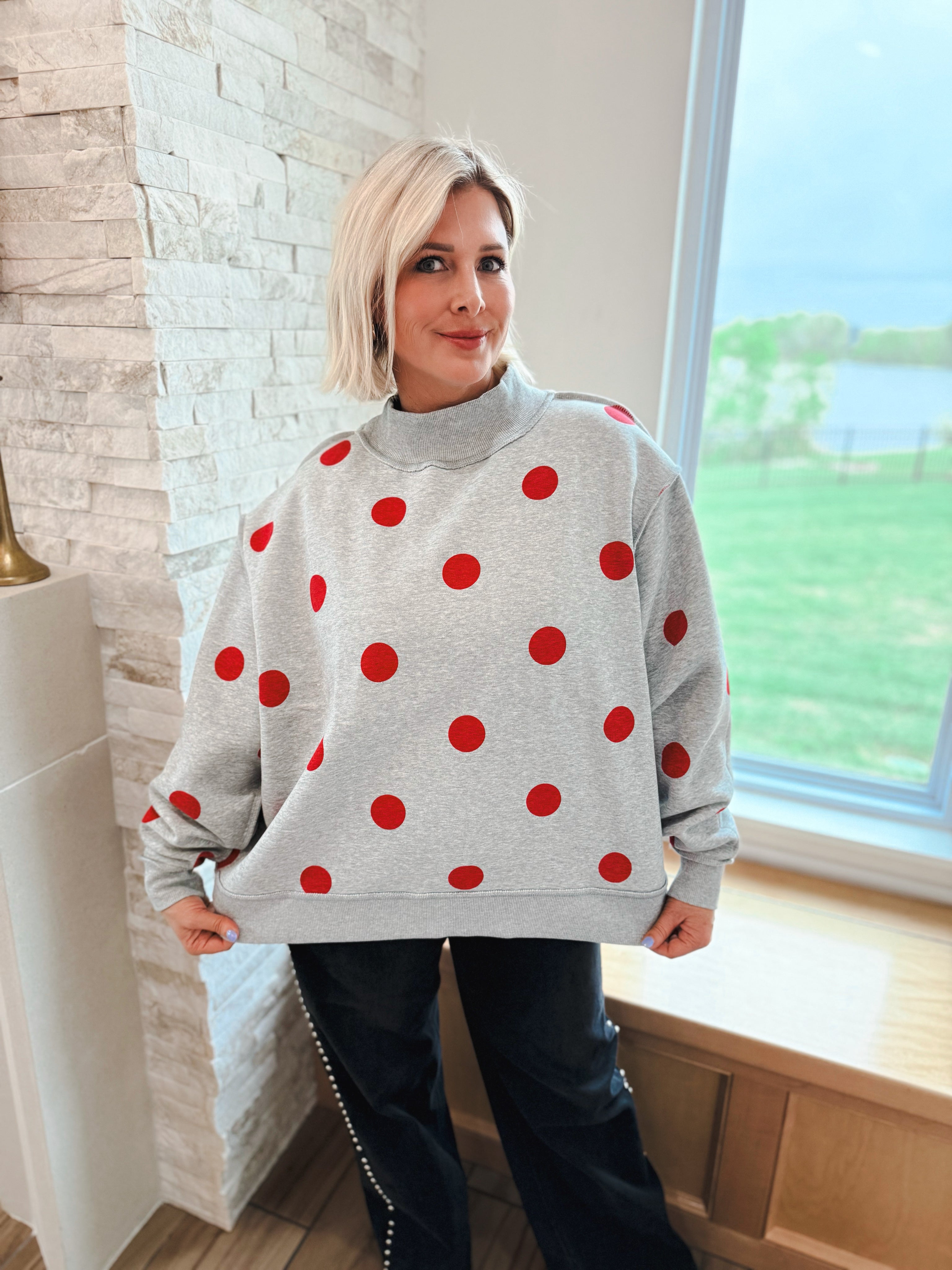Grey oversized sweatshirt with red polka dots and a mockneck collar.