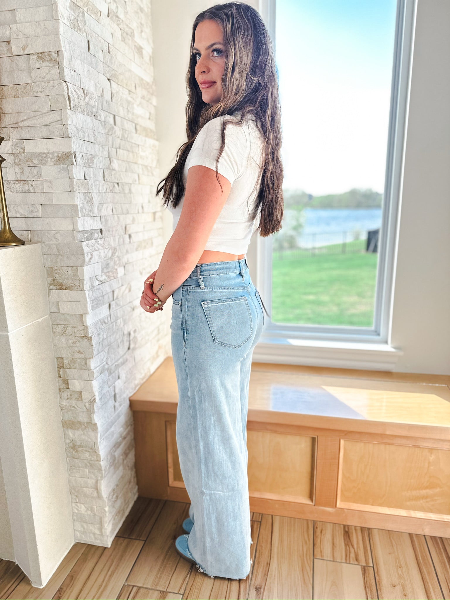 Woman in MICA LIGHT WASH WIDE LEG JEANS, featuring a light blue denim, high-waisted, and wide-leg silhouette with