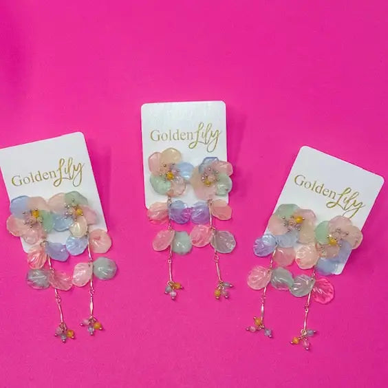 Spring floral dangle earrings with pastel colored flowers and leaf charms on white display cards.