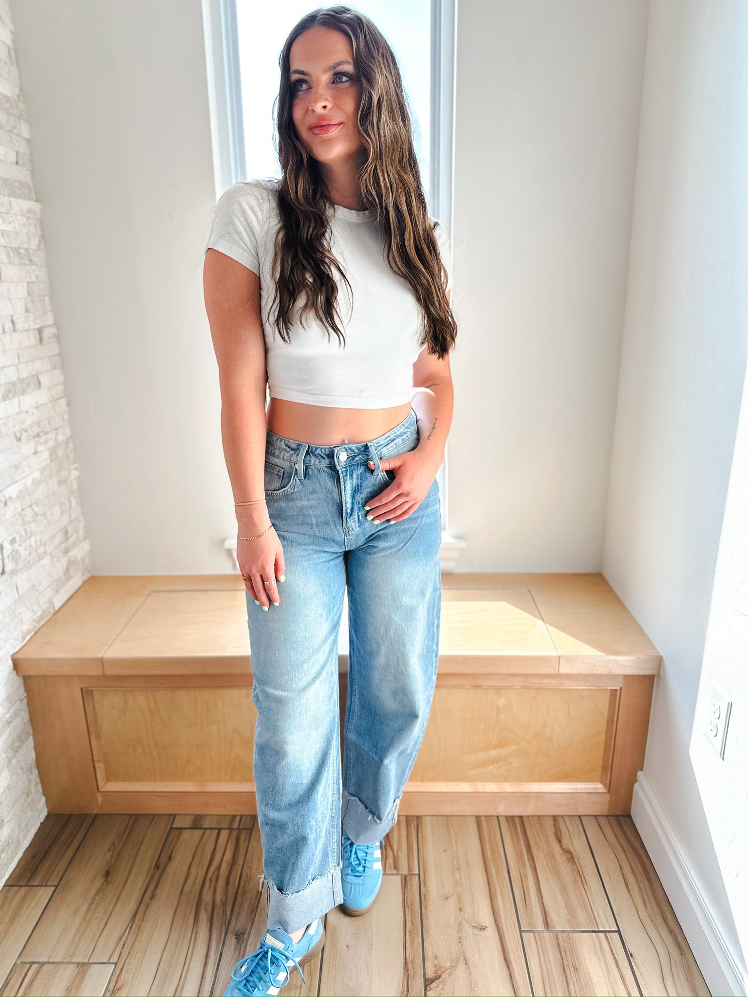 Model wearing MICA light wash cuffed barrel jeans and a white crop top, styled with blue sneakers. High-waisted denim with