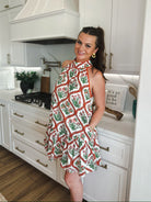 Entro red and cream floral halter mini dress with ruffled hem. Woman wearing dress in a kitchen.
