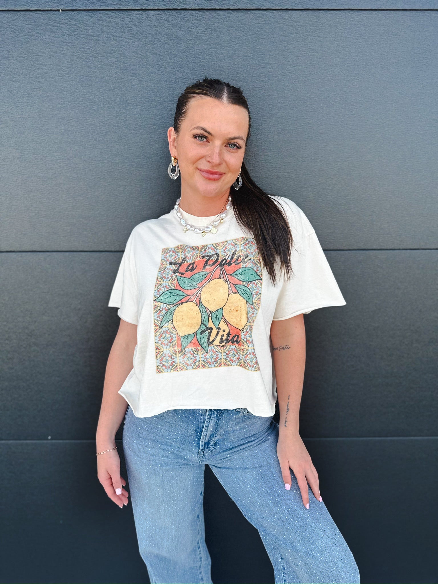 Cream La Dolce Vita vintage crop tee with a colorful graphic of lemons and "La Dolce Vita" text on a patterned background.