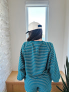 Teal and white striped long sleeve top and elastic waist shorts set worn by a person facing away, wearing a cream baseball