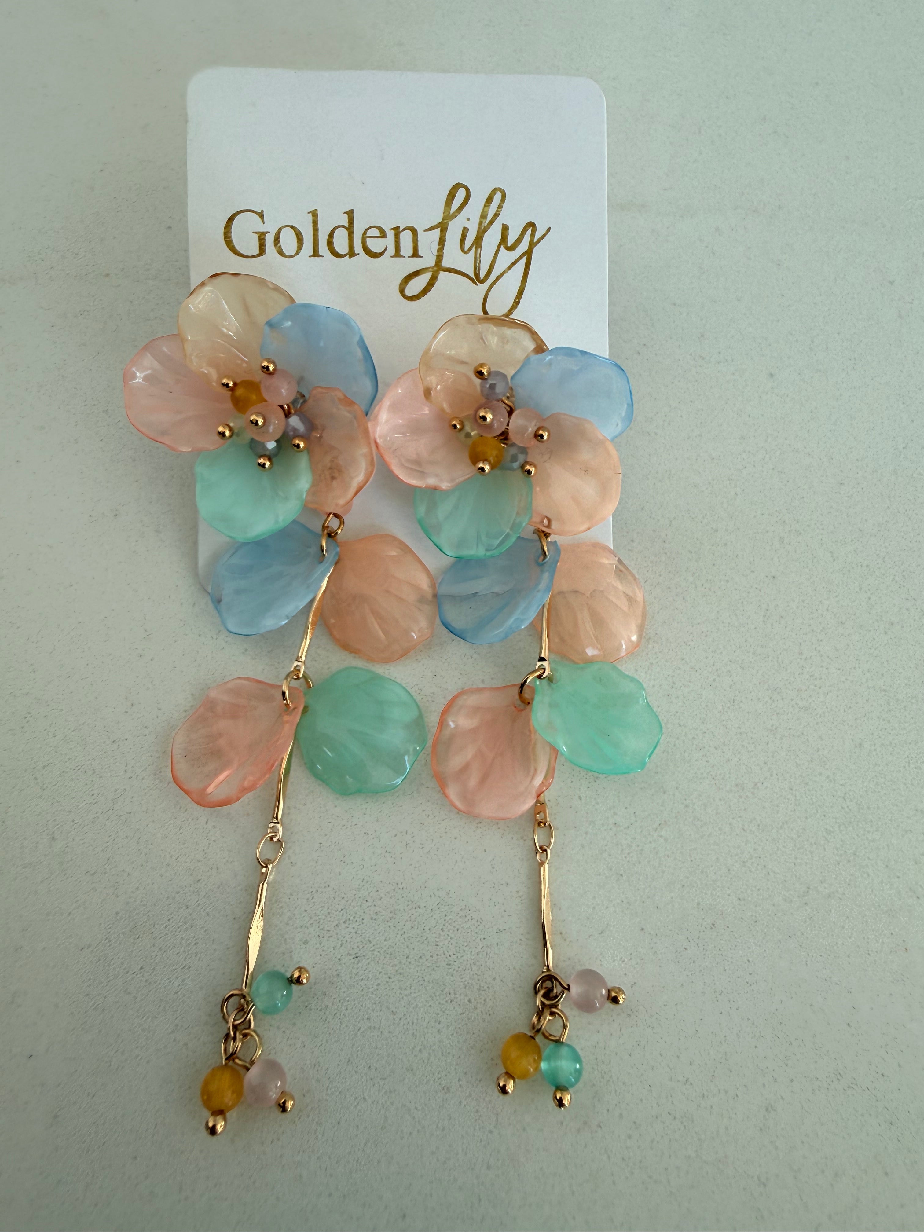 Gold colored dangle earrings featuring pastel floral petals in pink, blue, and mint green, with small beaded drops at the