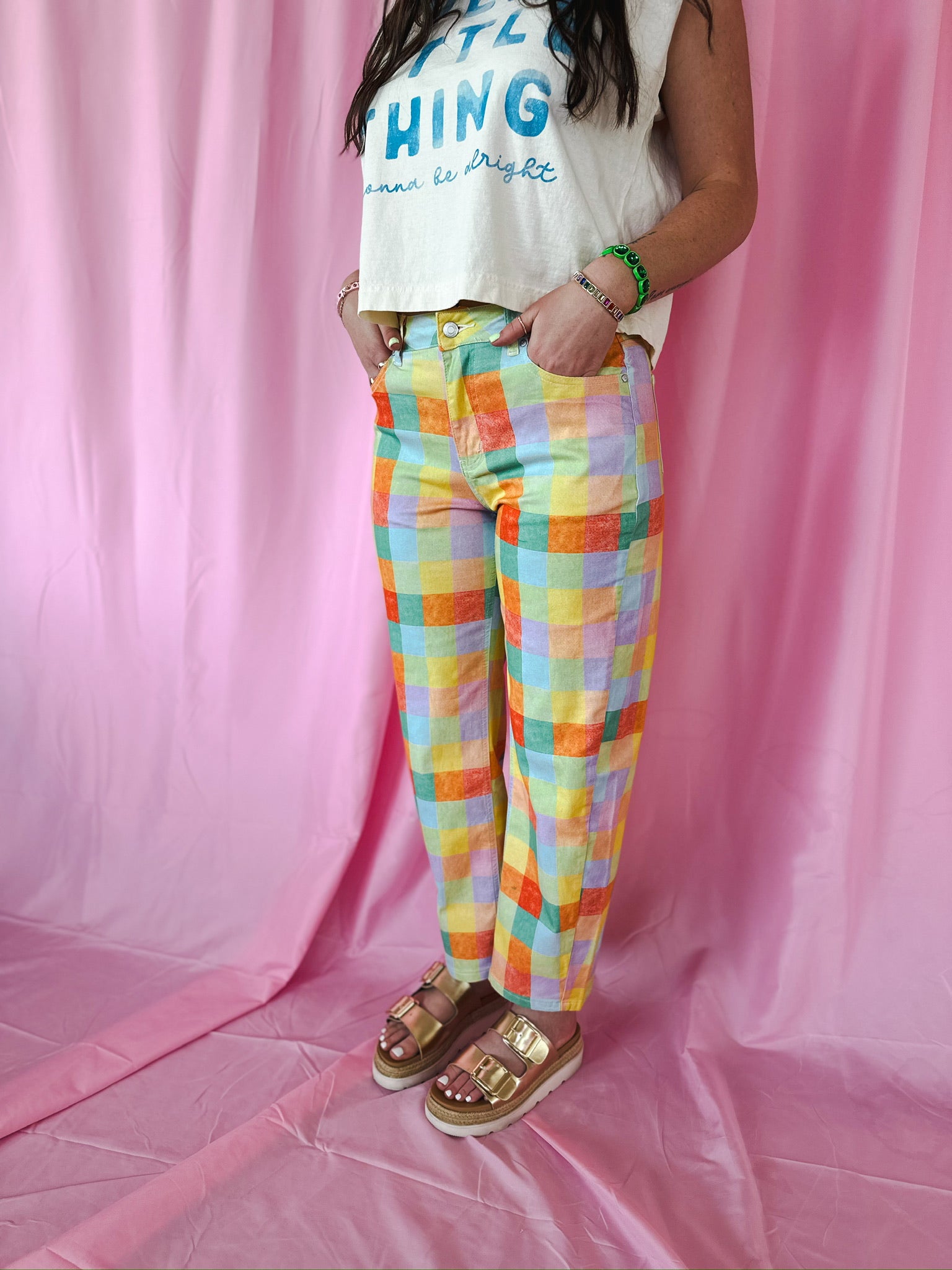 High waist barrel pants in a colorful plaid pattern with red, orange, yellow, blue, and purple squares. Model wears gold