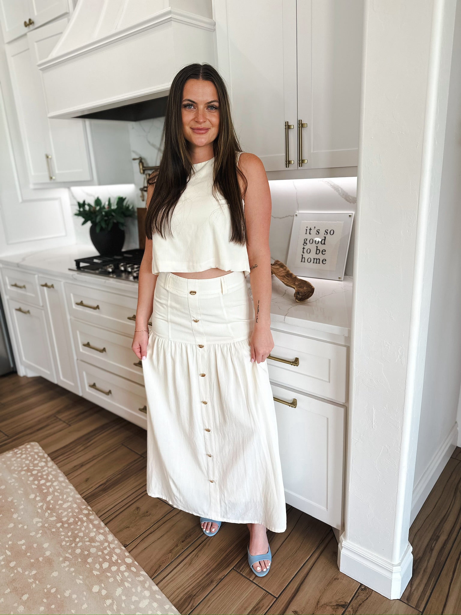 Woman in cream matching set featuring a cropped sleeveless top and a long button-front skirt.
