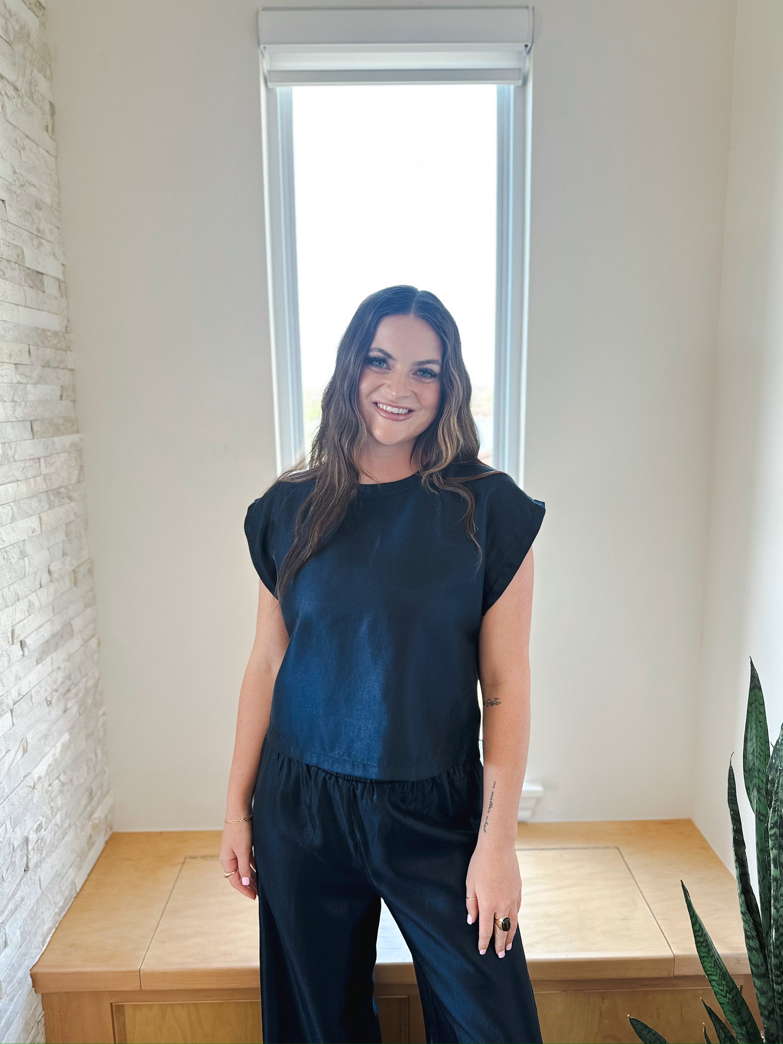 Woman wearing a navy shimmer short sleeve top and matching wide-leg pants, part of an elevated matching set.