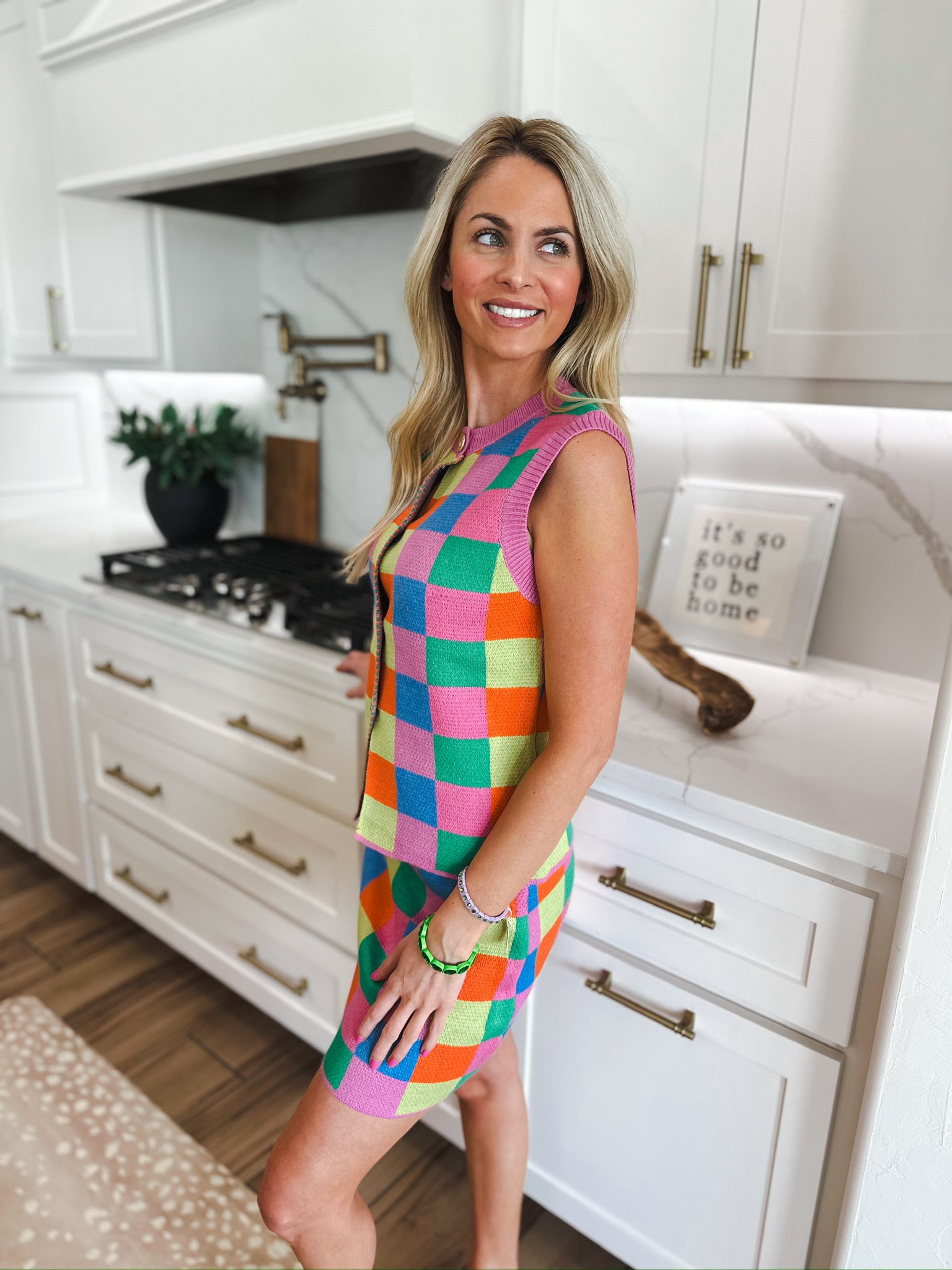 Woman in a multicolor checker knit tank and midi skirt set featuring pink, blue, green, orange, and yellow squares.