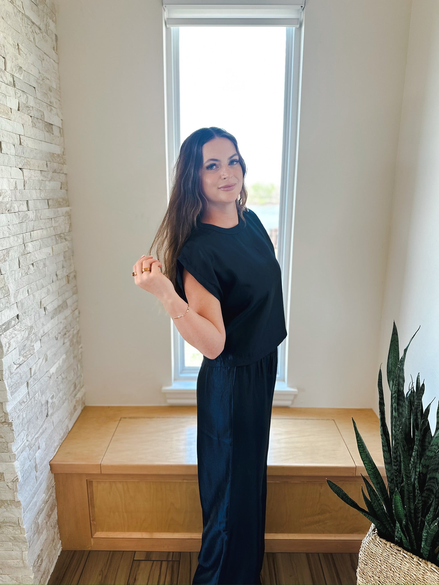 Woman in black shimmer matching set: short-sleeve top and wide-leg pants.