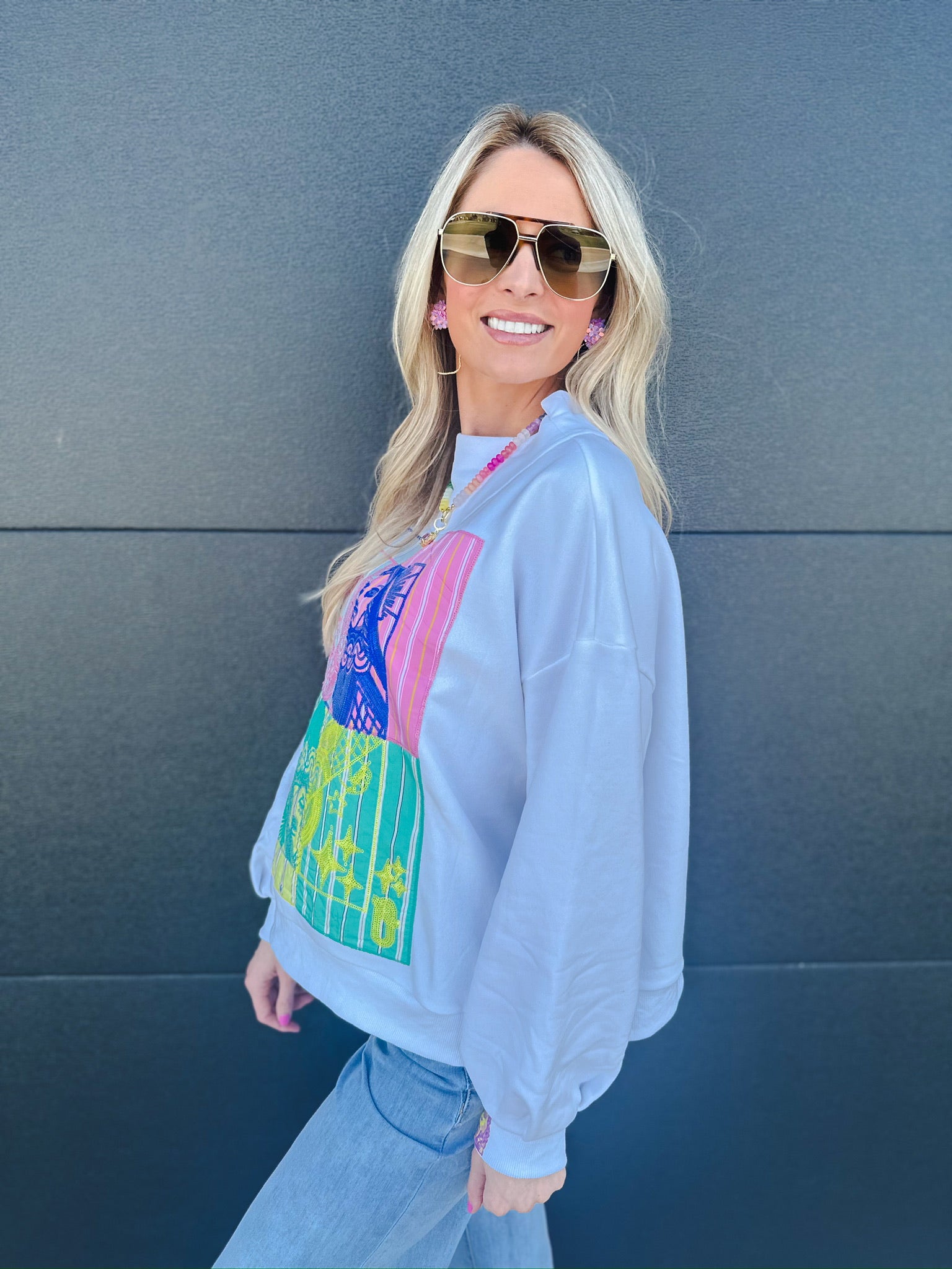 White Queen of Sparkles sweatshirt with a colorful patchwork graphic on the front, featuring mock neck and long sleeves.