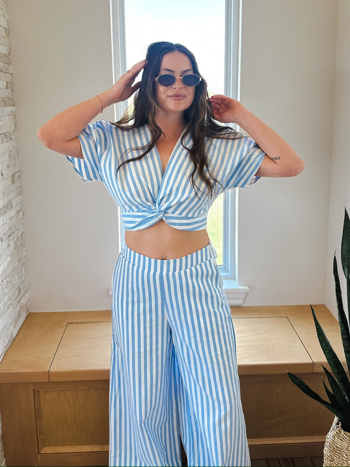 Woman wearing a blue and white striped twist front crop top and matching wide-leg pants set. pants.