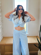 Woman wearing a blue and white striped twist front crop top and matching wide-leg pants set. pants.