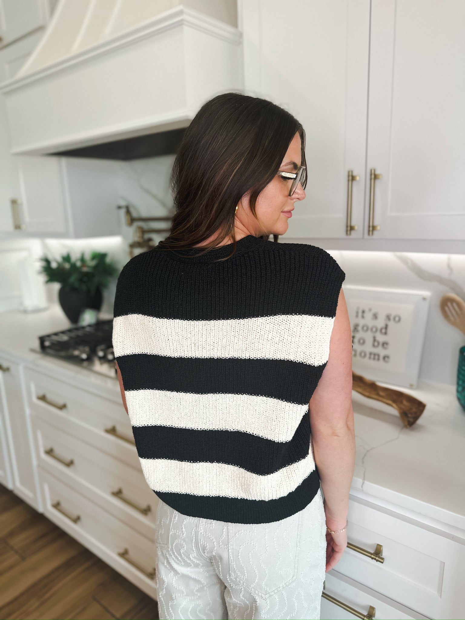 Back view of a women's preppy black and cream horizontal striped knit sweater vest.