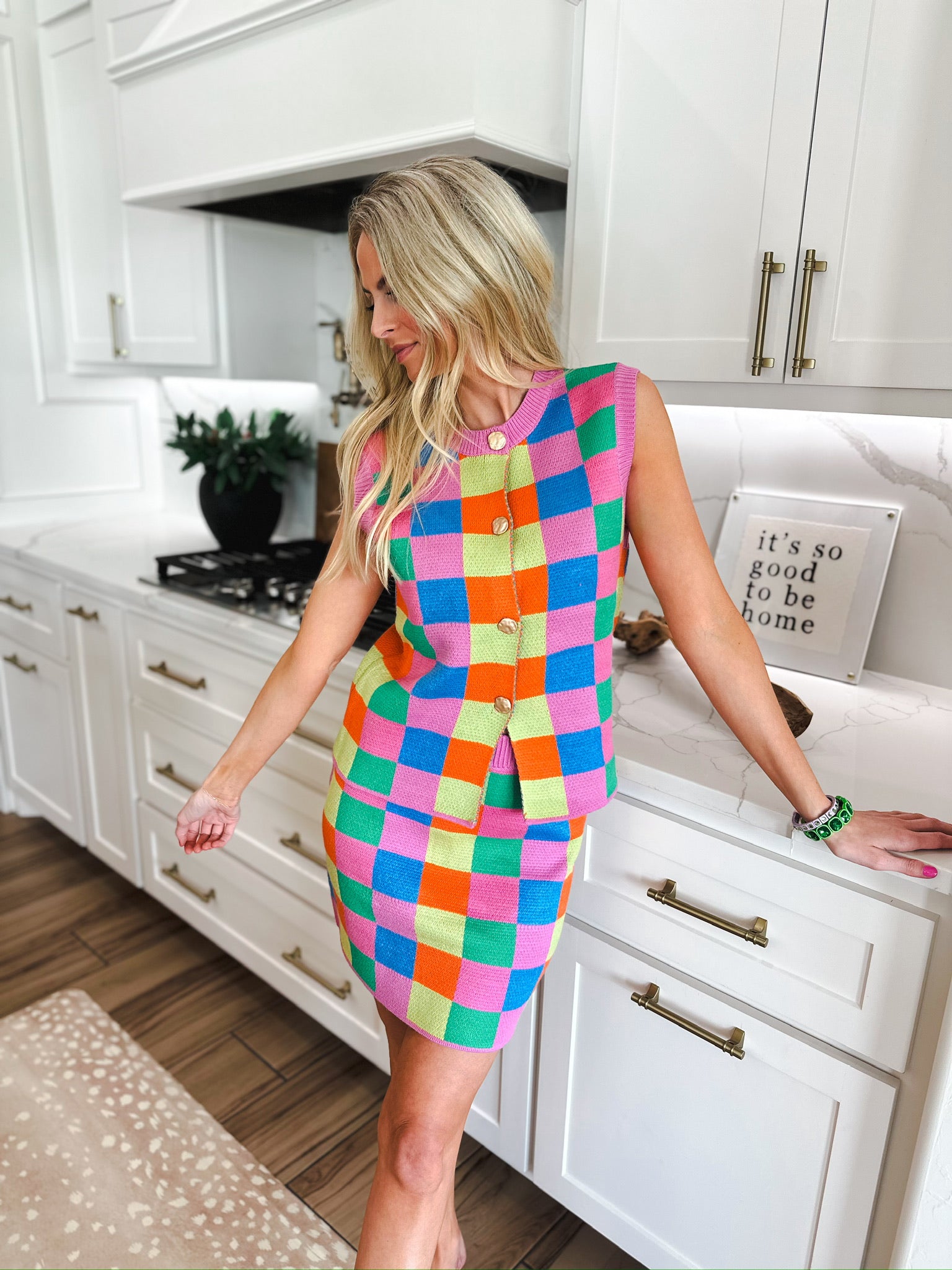 Woman wearing a multicolor checker knit tank top and midi skirt set with gold buttons.