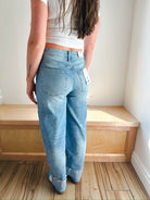 Model wearing light wash MICA barrel jeans with cuffed bottoms and white sneakers.