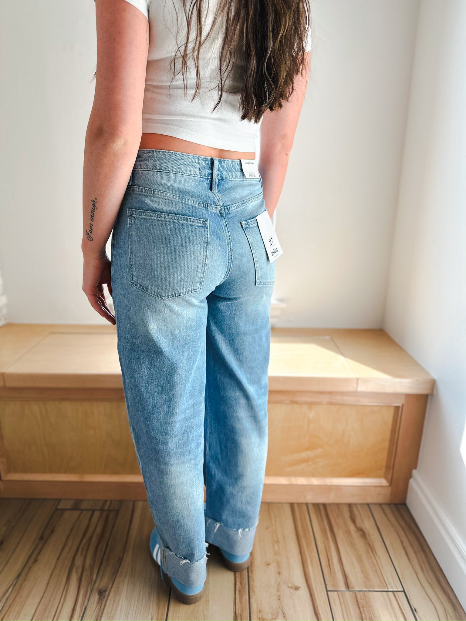 Model wearing light wash MICA barrel jeans with cuffed bottoms and white sneakers.