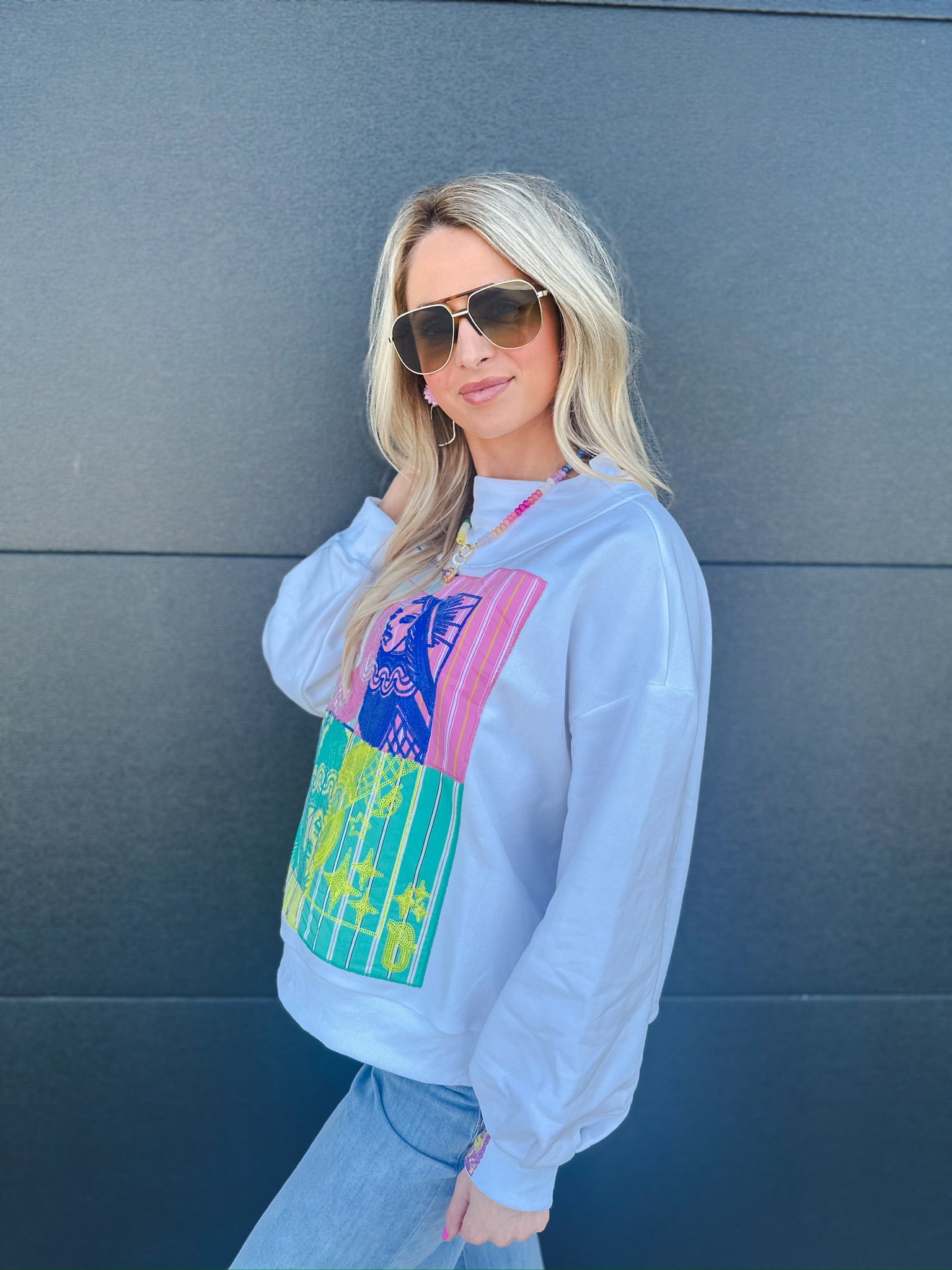 Queen of Sparkles white mock neck sweatshirt with vibrant colorblock patchwork featuring abstract designs and stripes
