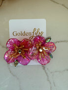 Large pink floral stud earrings with iridescent petals, gold beads, and crystal accents on a white card.