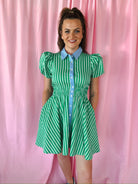 Entro green and white striped mini dress with puff sleeves, blue collar, and shirred waist. Woman smiling against pink