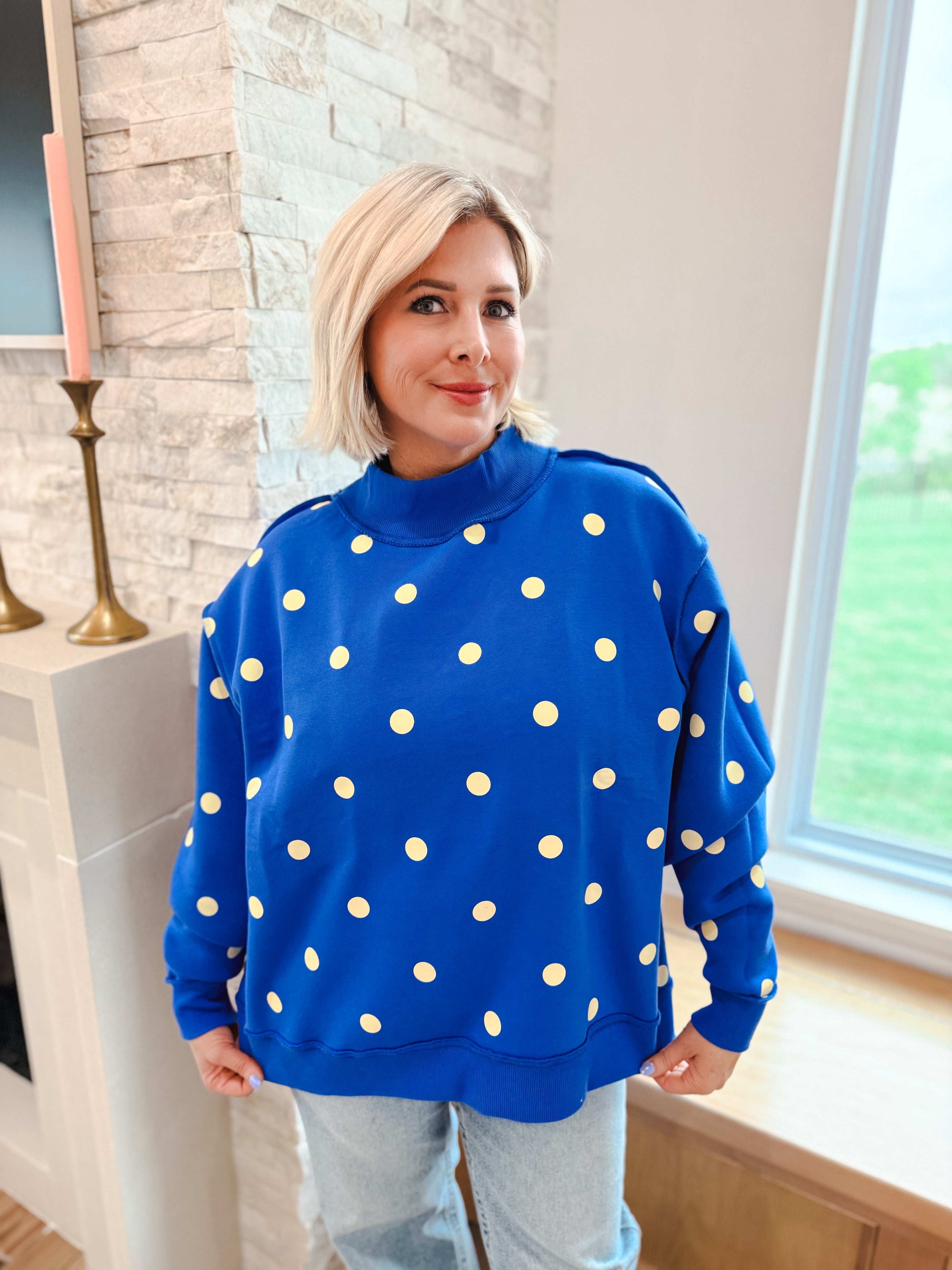 Poppy & Pine Royal Blue Oversized Sweatshirt with yellow polka dots and mockneck. Model wears light wash jeans.