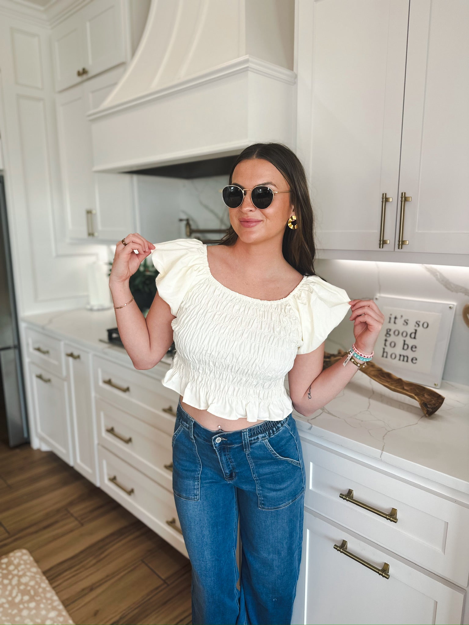 Cream ruched puff sleeve crop top with elasticated hem, paired with mid-rise blue denim cargo pants. Model wears sunglasses