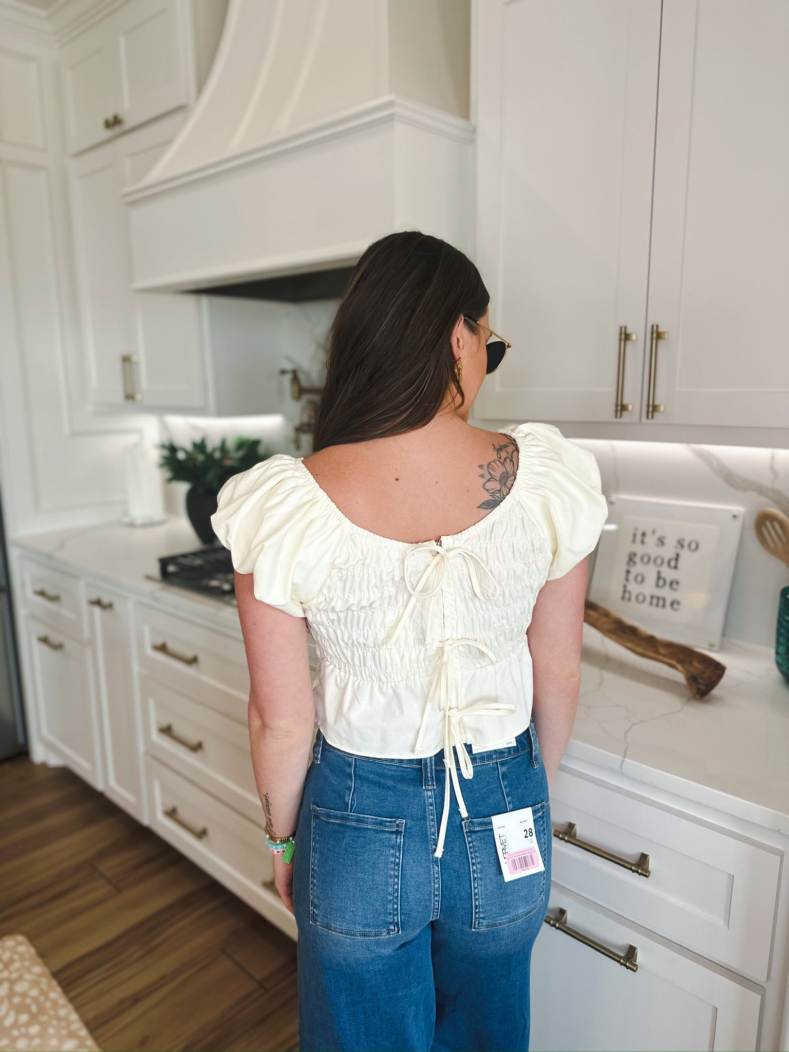 Soft yellow puff sleeve ruched blouse with back tie closure, worn with blue denim jeans.