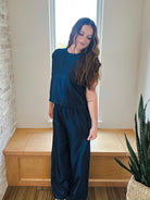 Woman wearing a navy shimmer matching set: short sleeve top and wide-leg pants. Elevate your style.