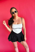 Black & white colorblock athletic dress with pleated skirt and spaghetti straps. Woman wearing sunglasses and jewelry