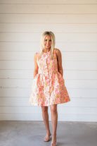 Bright pink floral brocade dress with a flared skirt, button front, and lime/yellow accents. Sleeveless design.