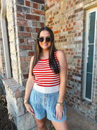 Woman wearing a cream and red stripe game day tank top and light wash denim shorts with buttons.
