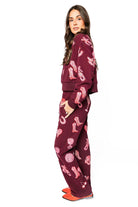 Dark plum henley sweatshirt and pants with all-over pink disco cowgirl icons like boots, cherries, and wine glasses.