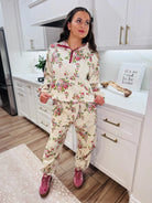 A woman models the Davi & Dani floral half-zip set, featuring a cream base with a pink and green floral print, burgundy