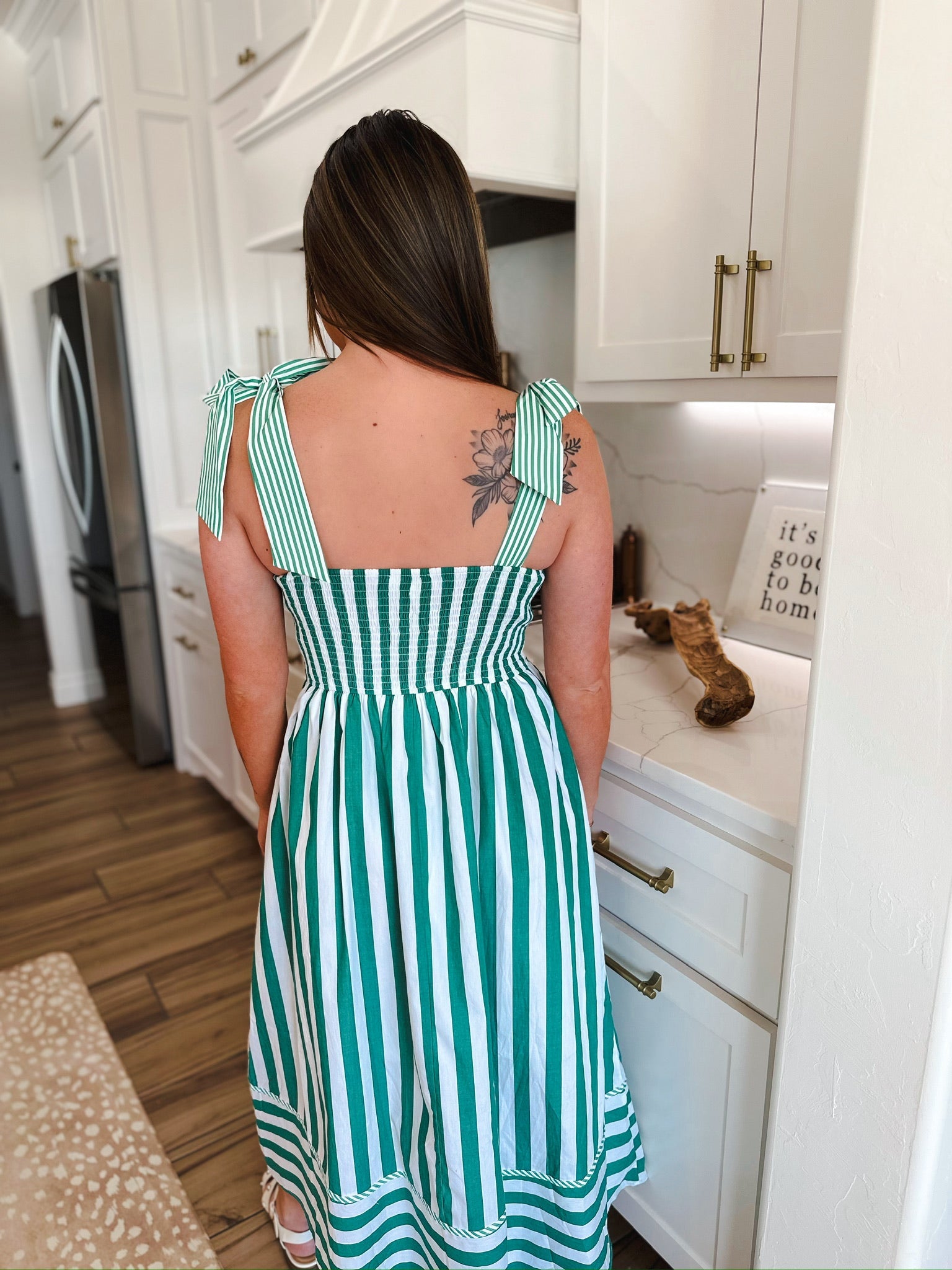 Woman from behind wearing a green and white striped midi dress with tie straps and a smocked bodice.